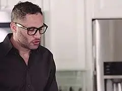 Zwei sexy Frauen in freizügiger Kleidung sitzen mit einem Mann an einem Küchentresen und blicken lüstern zu ihm herüber