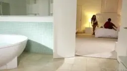 Nackte schwarze Lesbe steht lächelnd in der Dusche, während die weiße Frau vor ihr kniet und ihre nasse Muschi leckt.