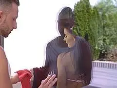Dunkelhaarige Schönheit im Profil mit laszivem Blick und geöffneten Lippen, hinter ihr ein Mann im weißen Tanktop.