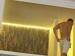 Zwei nackte Blondinen liegen entspannt und lasziv auf einer grauen Designer-Couch im modernen Wohnzimmer.