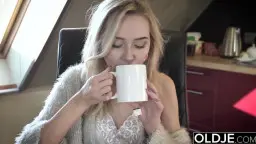 Blonde in grauem Cardigan trinkt Kaffee in Küche