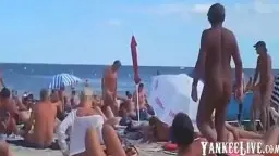 Nackter Mann steht vor Liegestühlen am Strand