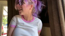 Blonde Frau mit lila Haaren und Brille lacht in die Kamera