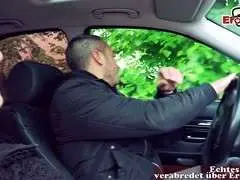 Junge brünette Schlampe lehnt lächelnd am Auto und schaut frech nach oben