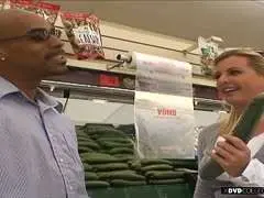 Selbstbewusster schwarzer Mann mit Sonnenbrille und gestreiftem Hemd lächelt vor einem Supermarkt in die Kamera.