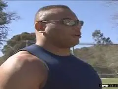 Durchtrainierter schwarzer Mann mit Sonnenbrille und Muskelshirt auf sonnigem Sportplatz