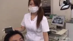 Japanische Zahnärztin mit Mundschutz und langen Haaren blickt erregt nach unten.